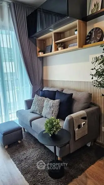 Cozy living room with modern gray sofa, stylish decor, and natural light from large window.