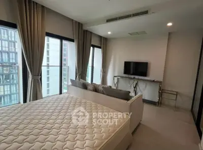 Modern bedroom with large windows and city view, featuring a stylish bed and wall-mounted TV.