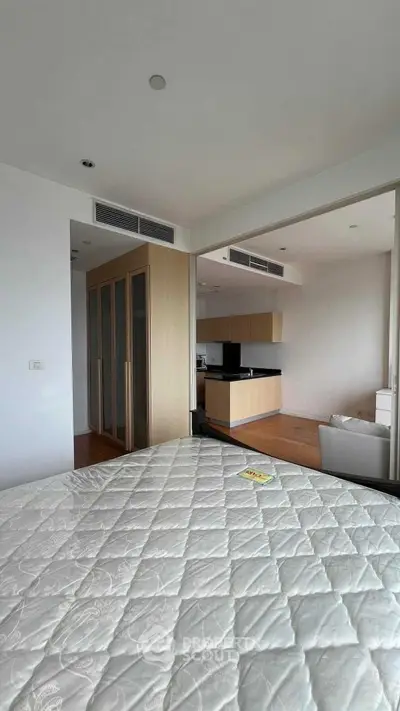 Modern bedroom with open layout to kitchen, featuring sleek design and ample natural light.