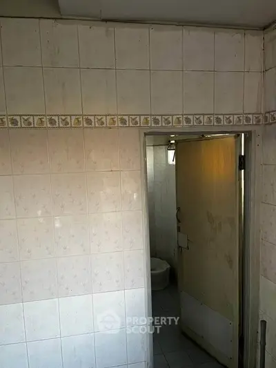 Small bathroom with tiled walls and a partially open door.