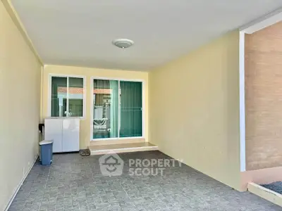 Spacious covered patio with tiled flooring and sliding glass doors, perfect for outdoor relaxation.