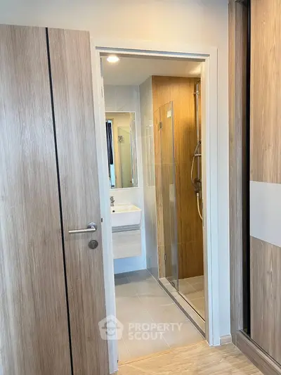 Modern bathroom with sleek wooden accents and glass shower enclosure