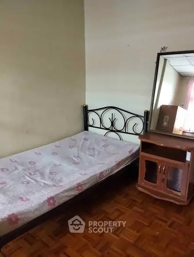 Cozy bedroom with single bed and wooden dresser, perfect for a minimalist lifestyle.