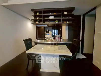 Modern kitchen with sleek black and white design, featuring a marble dining table and open shelving.