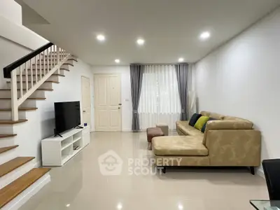 Spacious modern living room with elegant staircase and cozy seating area.
