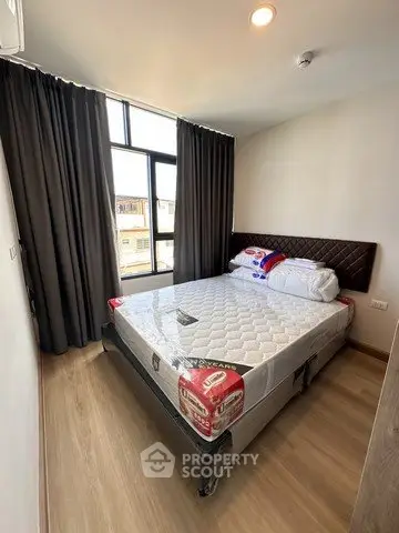 Modern bedroom with large window and new mattress in a stylish apartment.