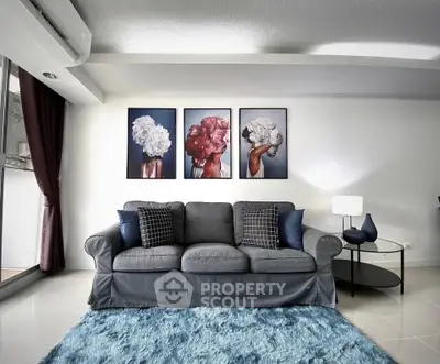 Stylish living room with modern decor and vibrant artwork, featuring a cozy sofa and plush blue rug.