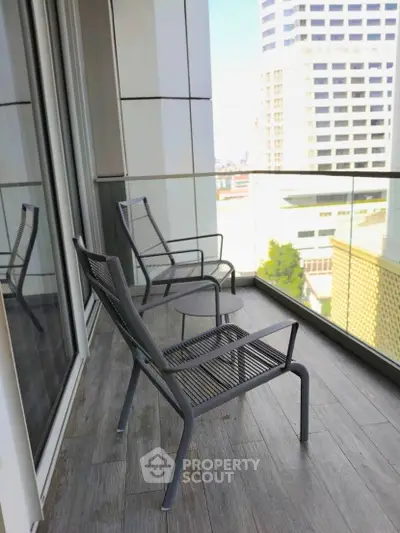 Modern balcony with city view and stylish outdoor seating in urban high-rise apartment.