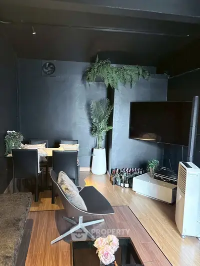 Modern living room with sleek black walls, stylish furniture, and a large TV, perfect for urban living.