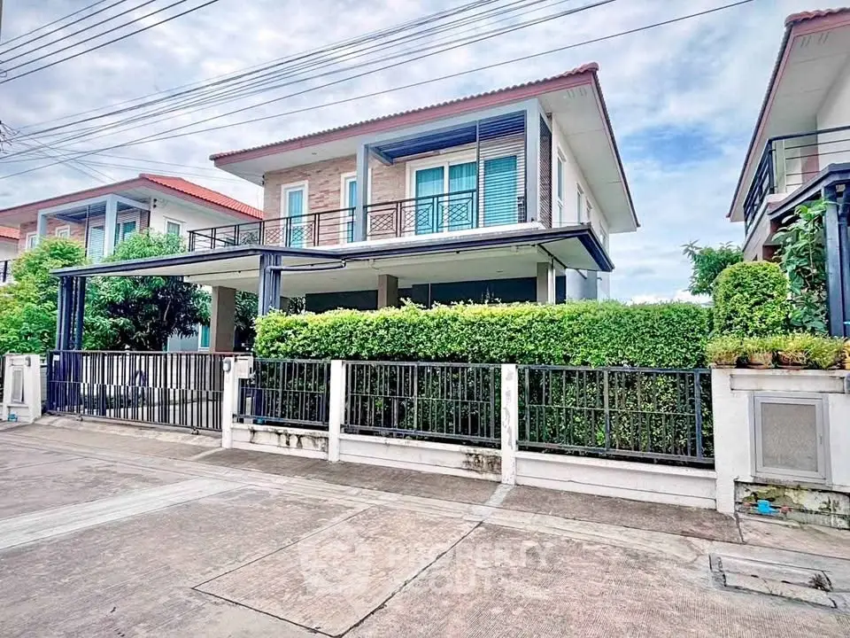 Modern two-story house with lush greenery and spacious driveway in a serene neighborhood.