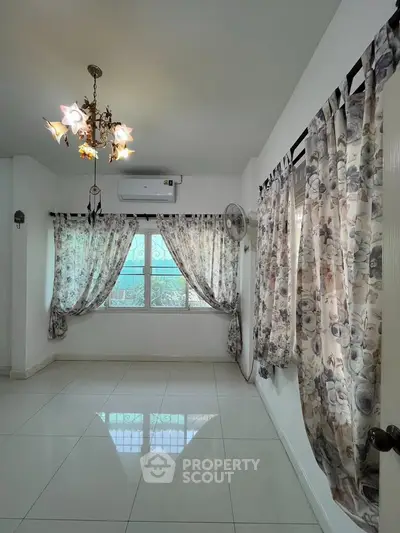 Bright and airy room with elegant chandelier and floral curtains, perfect for a cozy living space.