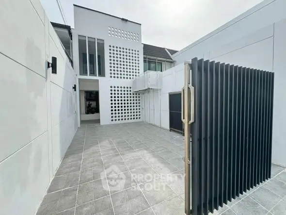 Modern minimalist exterior with sleek design and spacious tiled courtyard.