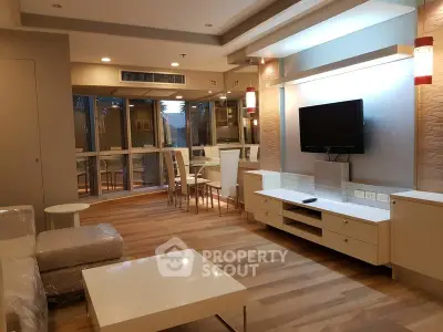 Modern living room with stylish furniture and wooden flooring, featuring a wall-mounted TV and elegant lighting.