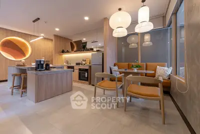 Modern kitchen with open layout and stylish lighting, featuring a central island and dining area.