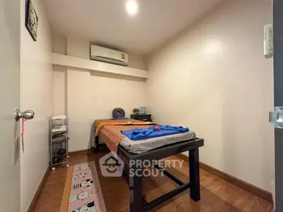 Cozy bedroom with wooden flooring and air conditioning, perfect for relaxation.