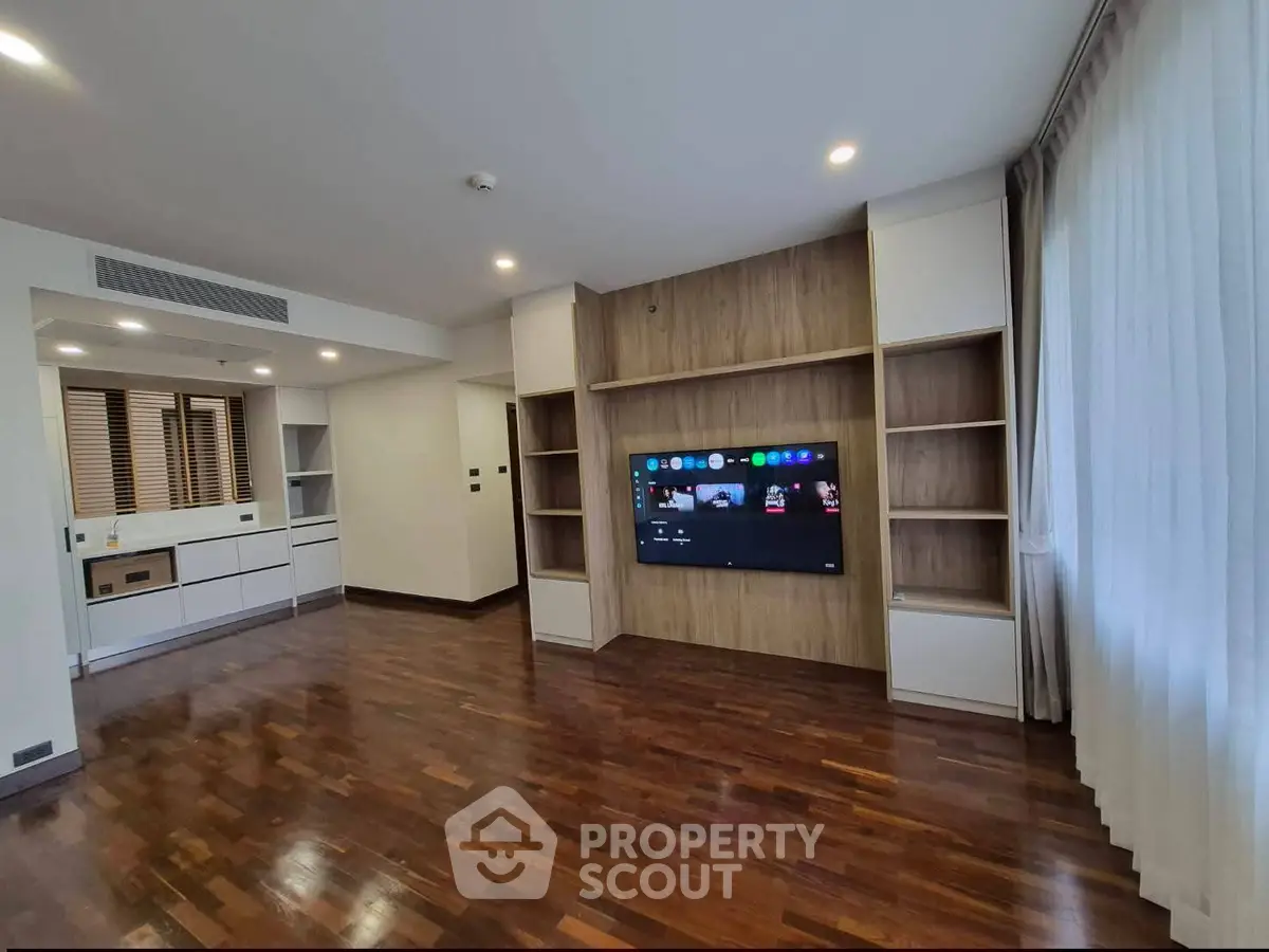 Spacious modern living room with wooden flooring and built-in entertainment unit.