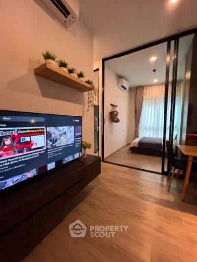 Modern apartment interior with open living area and bedroom, featuring sleek design and natural light.