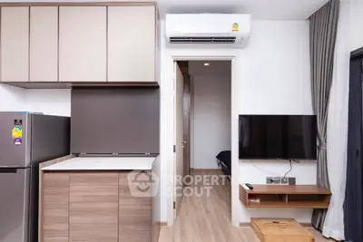 Modern apartment interior with sleek kitchen and cozy living area, featuring wood flooring and contemporary design.
