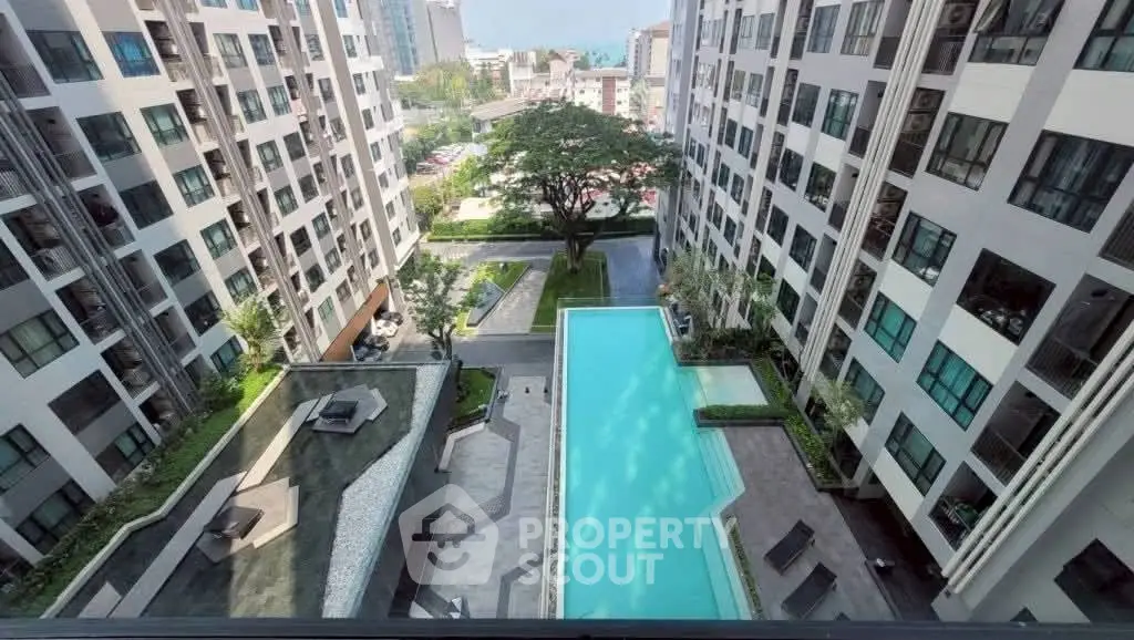 Stunning aerial view of modern apartment complex with pool and lush greenery.