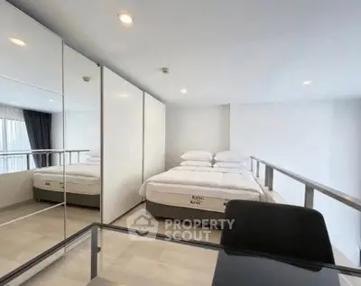 Modern bedroom with mirrored wardrobe and sleek design in a contemporary apartment.