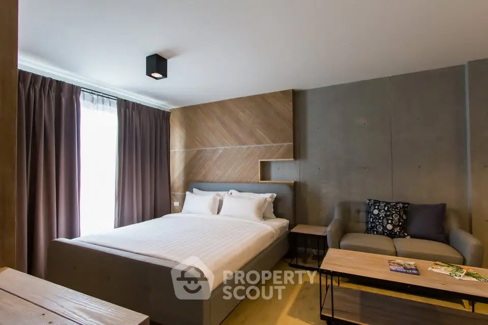 Modern bedroom with stylish decor and cozy seating area, perfect for relaxation.