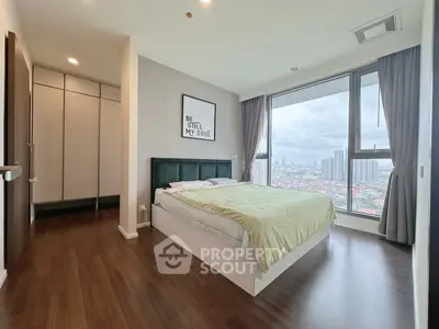 Modern bedroom with large window and city view, featuring stylish decor and ample natural light.