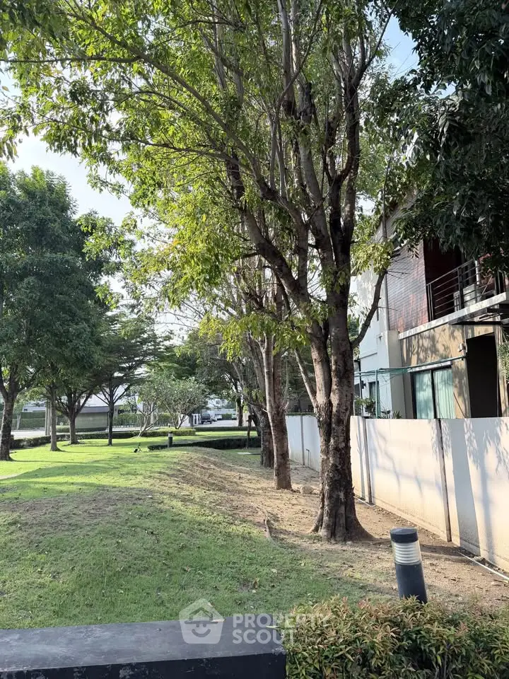 Spacious garden area with lush trees and modern building facade