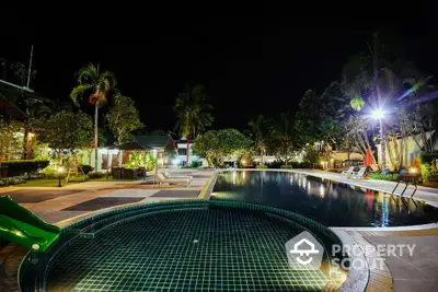 Luxurious night view of a resort-style swimming pool with lush landscaping.