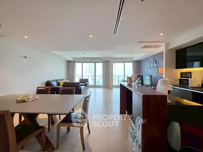 Spacious open-layout living room with modern kitchen and large windows.