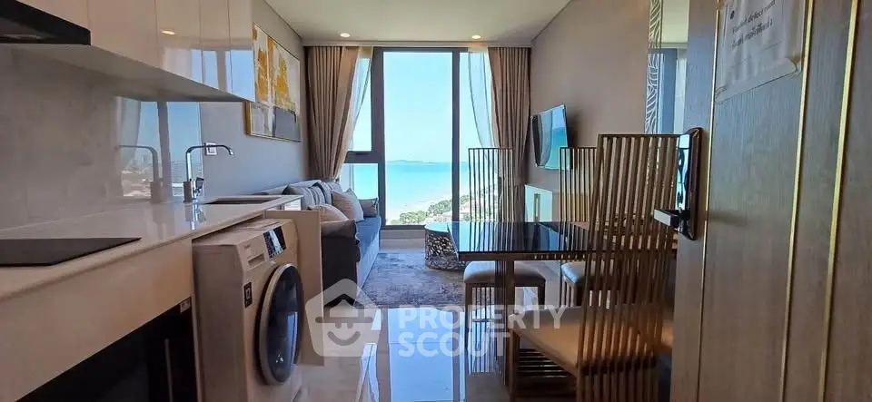 Modern apartment with ocean view, featuring sleek kitchen and cozy living area.