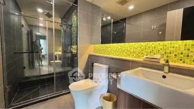 Modern bathroom with glass shower and stylish green tile accents