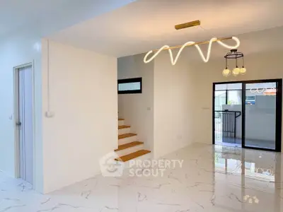 Modern interior with stylish lighting and marble flooring, featuring a staircase and large windows.