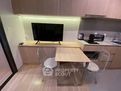 Modern kitchen with sleek cabinetry and cozy dining area in a stylish apartment.