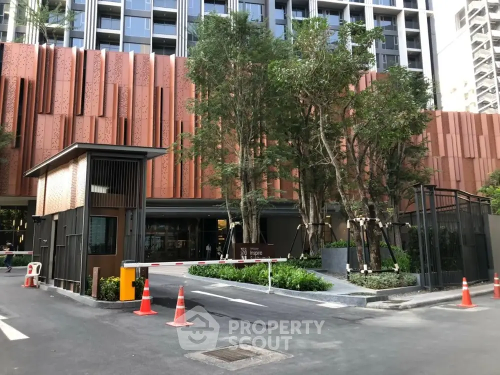 Modern building entrance with lush landscaping and security gate.