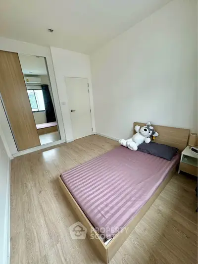 Cozy bedroom with wooden flooring and mirrored wardrobe, perfect for a serene living experience.