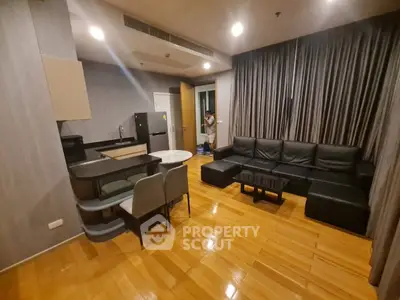Modern living room with sleek black furniture and open kitchen layout