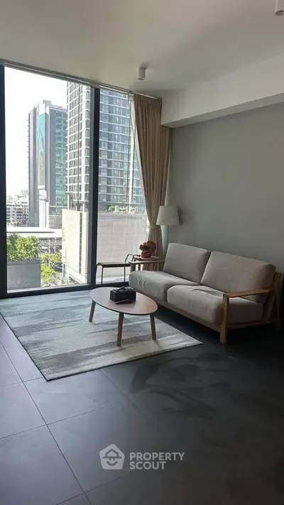 Modern living room with large windows and city view, featuring stylish furniture and natural light.