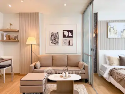 Modern living room with beige sofa, stylish decor, and cozy ambiance in open-plan apartment.
