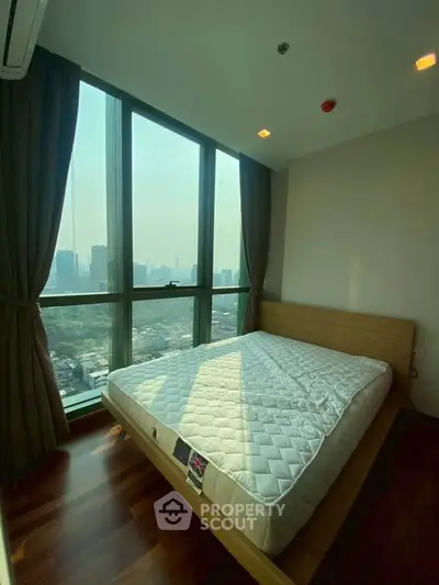 Spacious bedroom with large windows offering stunning city views in a modern high-rise apartment.