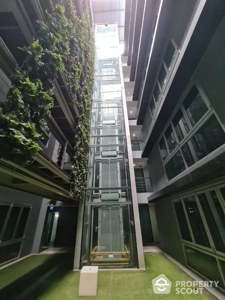 Modern building with glass elevator and vertical garden