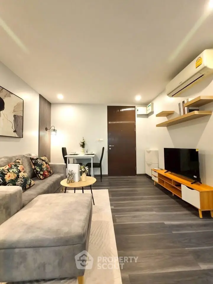 Modern living room with stylish decor, featuring a cozy sofa, wall-mounted TV, and elegant dining area.