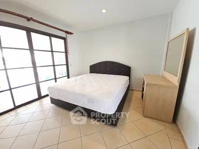Spacious bedroom with large windows and modern furnishings, perfect for comfort and relaxation.
