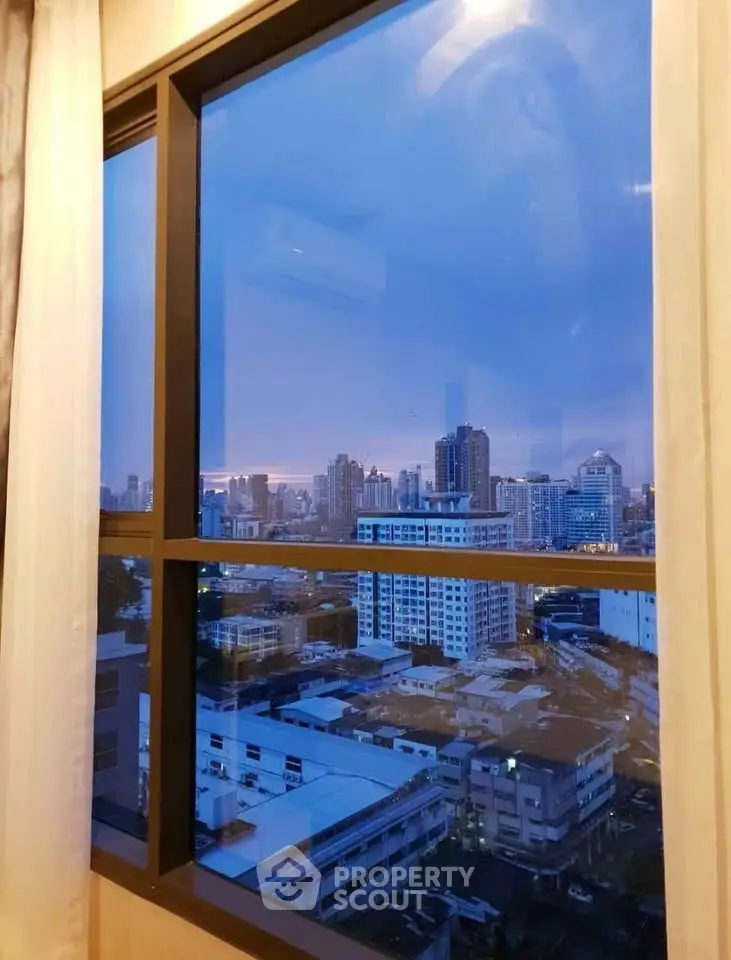 Stunning cityscape view from a high-rise apartment window at dusk, showcasing urban skyline.
