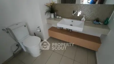 Modern bathroom with sleek sink and toilet, featuring elegant tile backsplash.