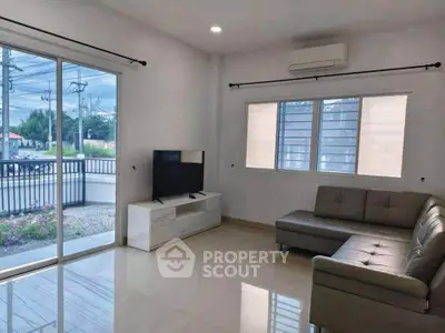 Modern living room with sleek furniture and large windows offering natural light and outdoor view.
