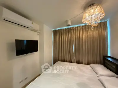Modern bedroom with elegant chandelier and wall-mounted TV, featuring a comfortable bed and air conditioning.