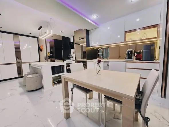Modern kitchen with sleek white cabinets and dining area, featuring ambient lighting and marble flooring.