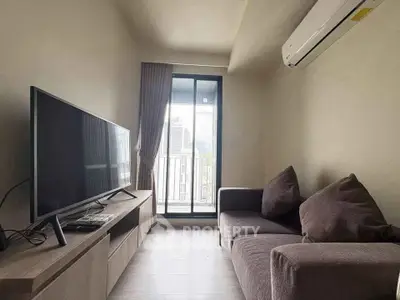 Cozy living room with modern sofa and large TV, featuring a balcony view.