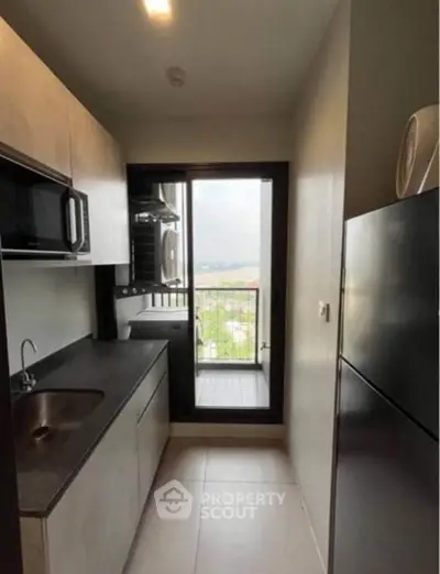 Modern compact kitchen with balcony view, featuring sleek cabinetry and appliances.