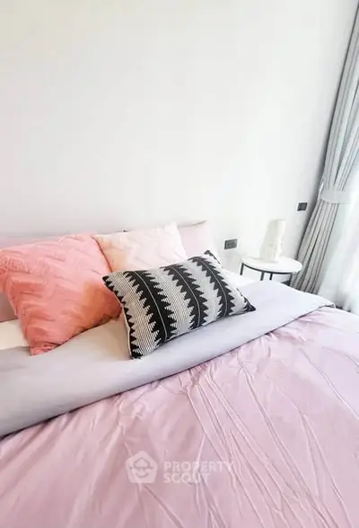 Cozy bedroom with stylish pillows and soft pink bedding, perfect for relaxation.
